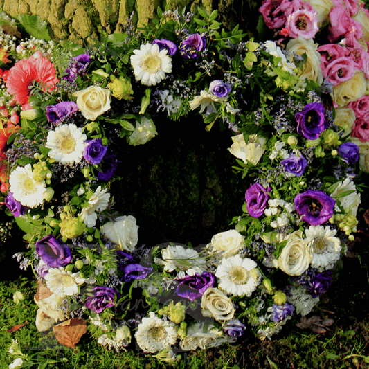 Corona fúnebre Balboa y morada con rosas blancas, gerberas y flor de lisianthus arreglo de condolencias